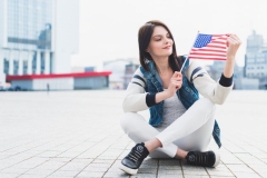woman-sitting-square-holding-american-flag-hand_23-2148157182
